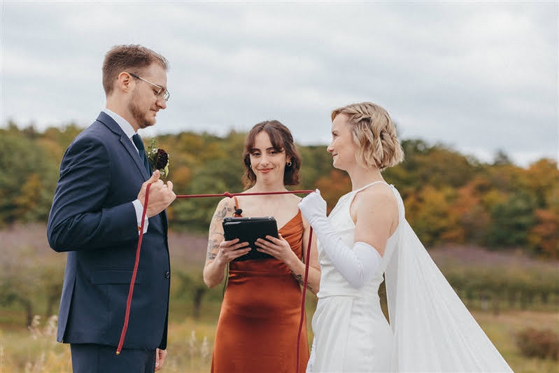 Bride and groom participating in a handfasting ceremony during their October wedding at Cherry Basket Farm. 