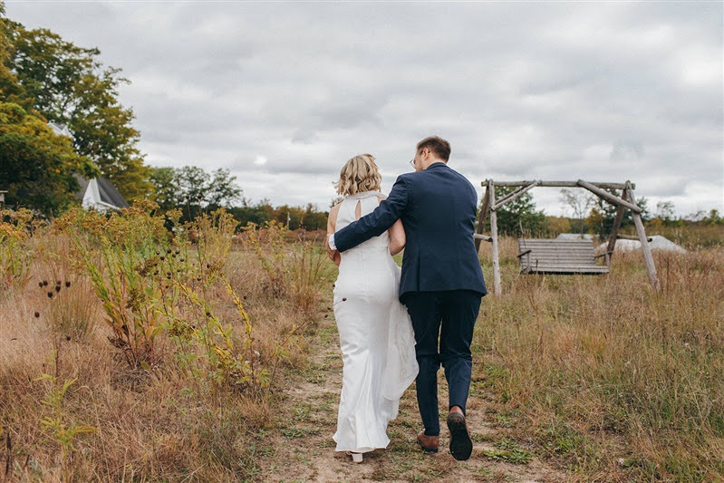 Bride and groom walking away together after their October wedding ceremony in Omena, Michigan. 