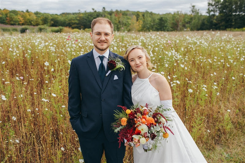 Couple posing on their wedding day in a cosmo flower field at Cherry Basket Farm in Suttons Bay.