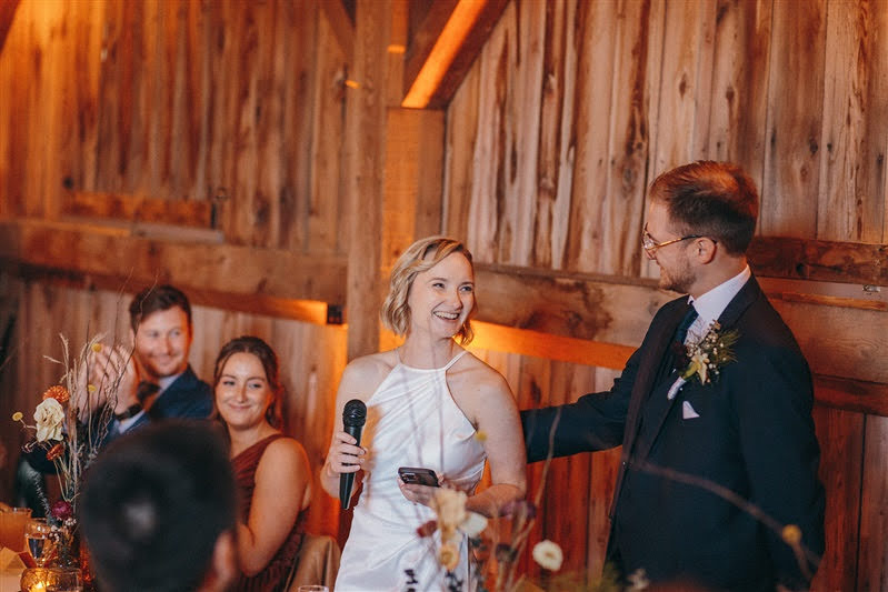 Bride and groom giving a welcome speech during their October wedding reception in a barn at Cherry Basket Farm. 