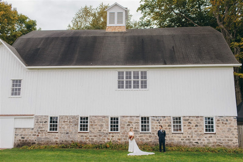 Bride and groom posing in front of Cherry Basket Farm during their couple portrait session. 